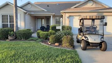 A residential house with a garage, a golf cart, and well-maintained landscaping.