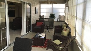 Un patio couvert aménagé avec des meubles en osier, une table et un ventilateur de plafond.
