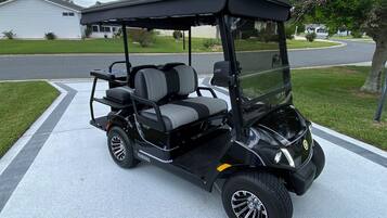 A black golf cart parked on a driveway.
