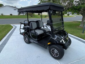 A black golf cart parked on a driveway. - 427 Santa Clara Cir (Lady Lake)