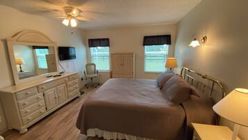 A bedroom with a bed, dresser, chair, and a ceiling fan.