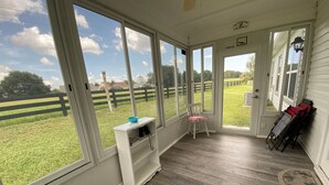 A room with large windows, a wooden floor, a white bench, and a chair with a pink cushion. - 427 Santa Clara Cir (Lady Lake)