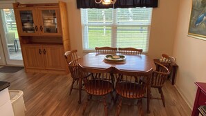 A dining area with a wooden table and chairs, a chandelier, and a window with blinds. - 427 Santa Clara Cir (Lady Lake)