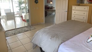 A bedroom with a bed, a dresser, and a door leading to a balcony. - 2066 Duval Ct (The Villages)