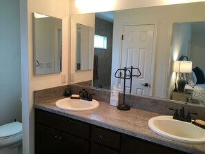A bathroom with two sinks, a large mirror, and a door. - 2315 Jans Ter (Wildwood)