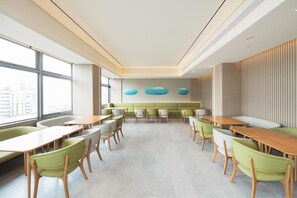 A modern interior with tables and chairs arranged in a spacious room with large windows and a high ceiling. - Ji Hotel Shenzhen Huaqiang North Electronic Buildi (Shenzhen)