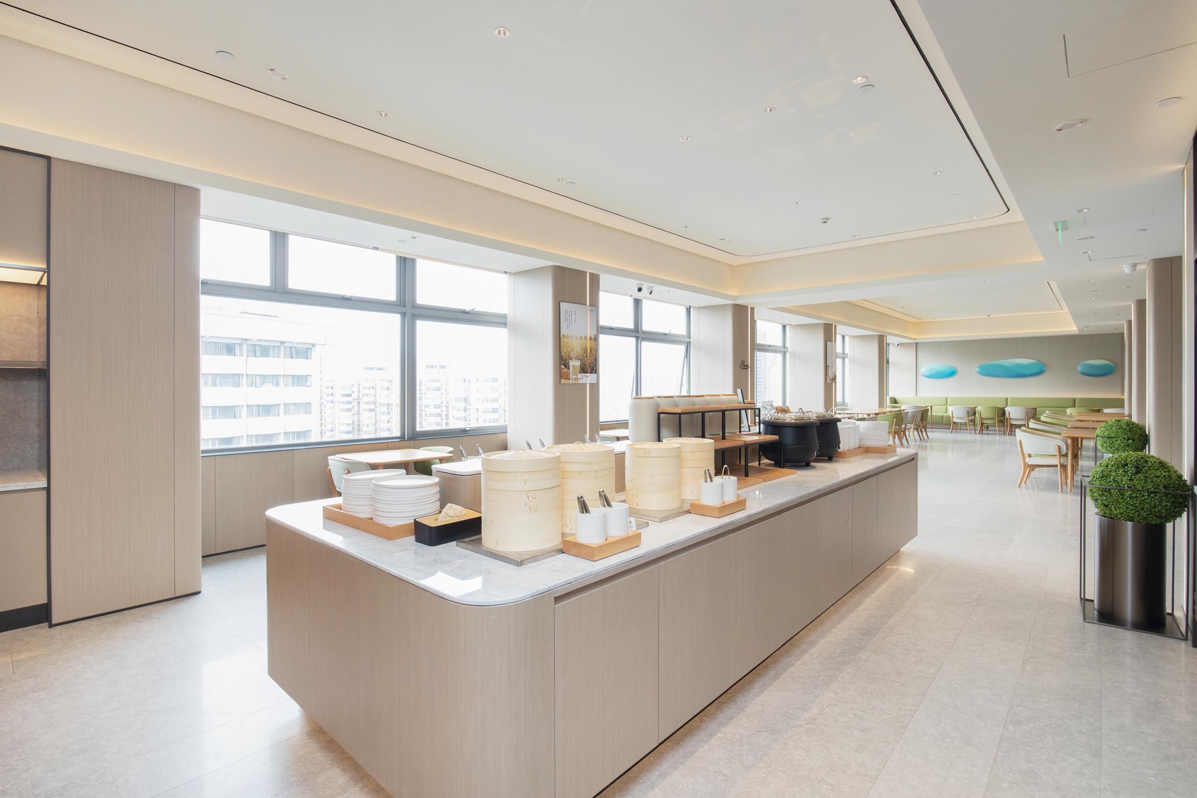 Un área de cocina moderna con una isla central, ventanas amplias y vista a la ciudad.
