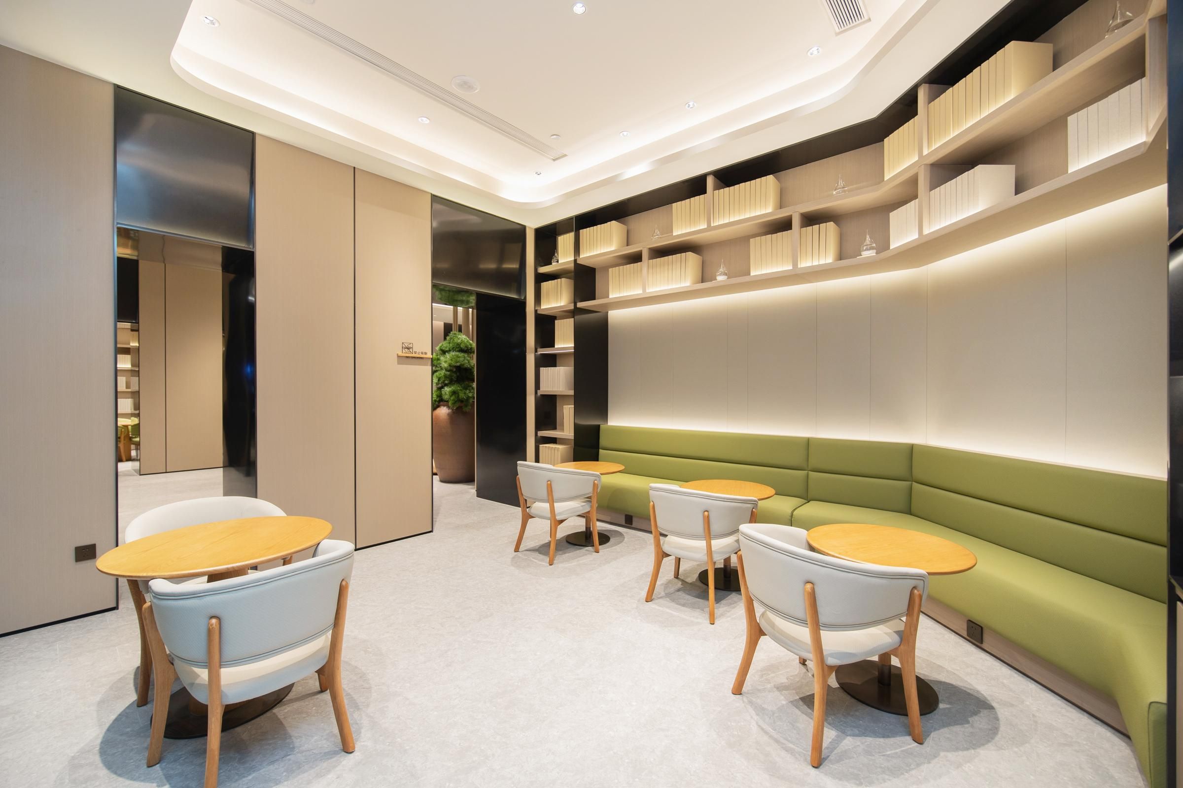 Un interior moderno con un sofá verde, sillas blancas y una mesa de madera.