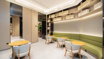 Un interior moderno con un sofá verde, sillas blancas y una mesa de madera.