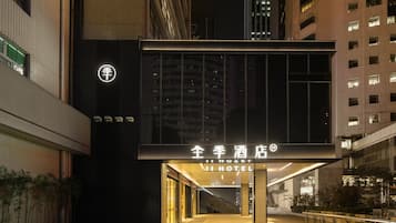 A hotel entrance with a modern design, featuring a prominent sign and a well-lit pathway leading to the entrance.