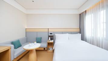 Una habitación de hotel moderna con una cama, un sofá, una mesita y una mesita de noche.