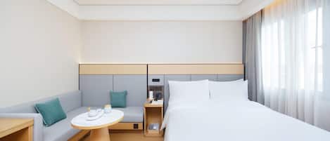 A modern hotel room with a bed, a sofa, a small table, and a nightstand.
