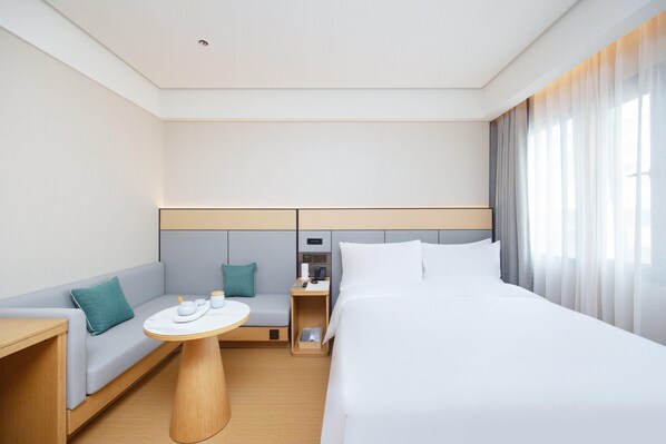 A modern hotel room with a bed, a sofa, a small table, and a nightstand. - Ji Hotel Shenzhen Huaqiang North Electronic Buildi (Shenzhen)