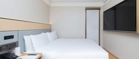 Una habitación de hotel con cama, mesita de noche, televisor y puerta.