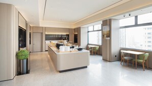 Eine moderne Hotelhalle mit einer zentralen Insellounge, Sitzgelegenheiten und großen Fenstern mit Blick auf die Stadt.