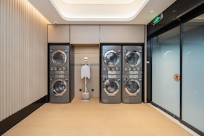 A modern laundry facility with four washing machines, a drying machine, and a ventilation unit. - Ji Hotel Shenzhen Huaqiang North Electronic Buildi (Shenzhen)