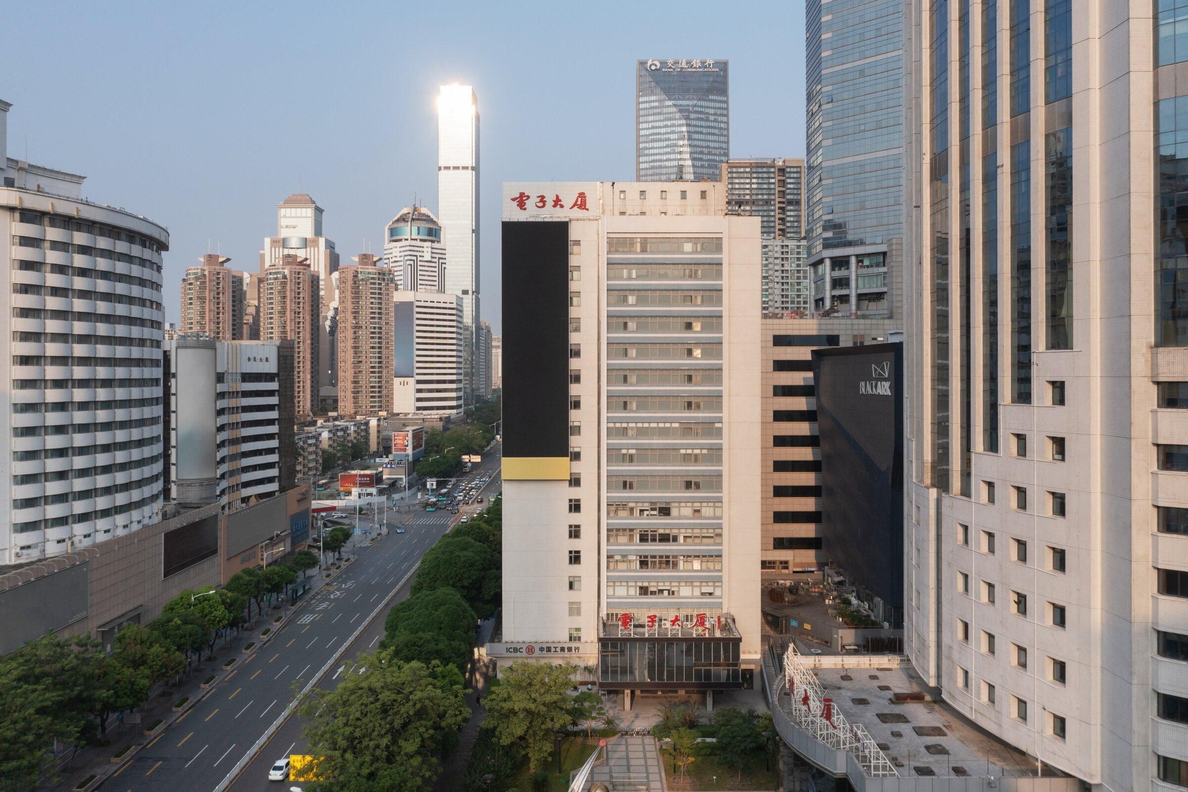 A high-rise building with a prominent sign, surrounded by other tall buildings and a busy street.
