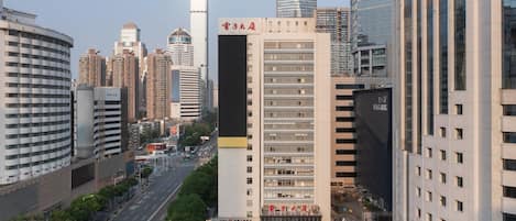 A high-rise building with a prominent sign, surrounded by other tall buildings and a busy street.