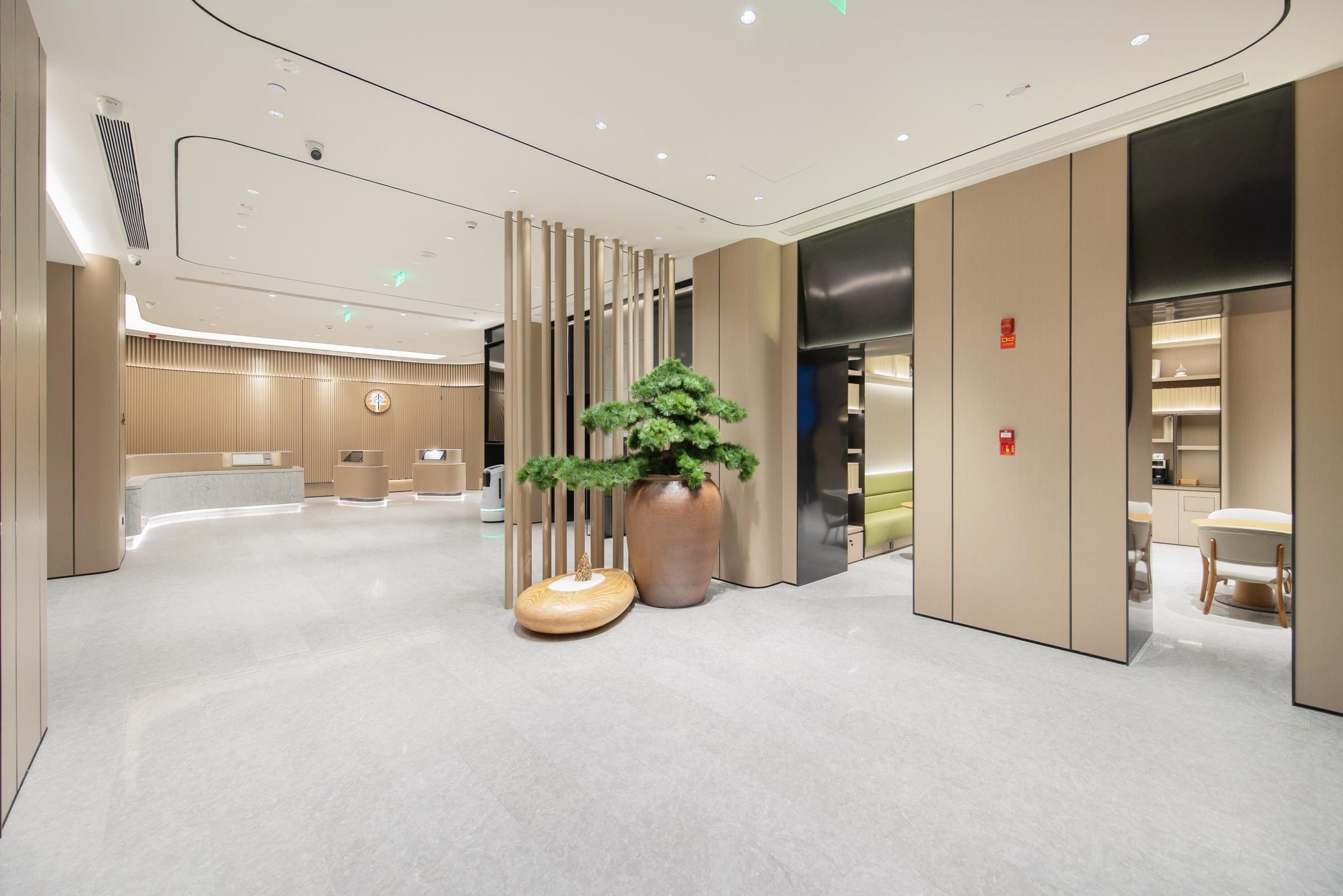 Un moderno vestíbulo de hotel con mostrador de recepción, una planta grande en maceta y una zona de estar.