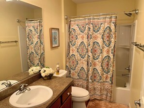 A bathroom with a sink, toilet, and shower curtain. - 2392 Hook Hollow Ter (The Villages)
