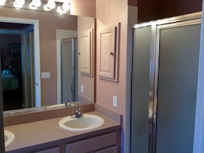 A bathroom with a sink, mirror, and a walk-in shower.