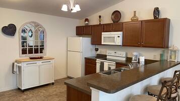 A kitchen with a central island, wooden cabinets, a microwave, stove, and a refrigerator.