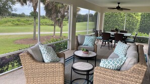 A covered patio with wicker furniture, a dining table, and ceiling fans. - 1468 Tidewater Ter (The Villages)