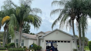 A residential house with a garage, surrounded by palm trees and a well-maintained lawn. - 1468 Tidewater Ter (The Villages)