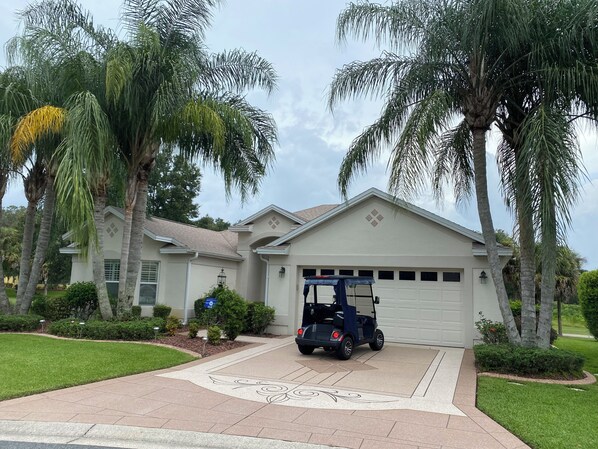 Una casa residenziale con un garage, circondata da palme e un prato curato.