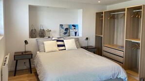 Une chambre à coucher avec un lit, des tables de chevet, une armoire et des œuvres d’art accrochées au mur.