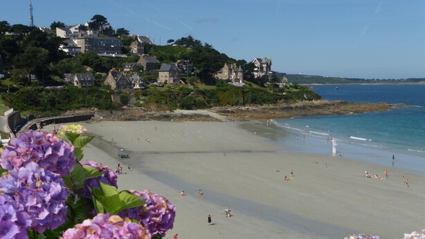 Une plage avec des gens, un pont et des maisons en arrière-plan.