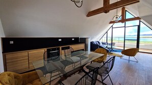 Une cuisine moderne avec une table à manger en verre, des meubles de rangement en bois et une grande fenêtre donnant sur l’extérieur.