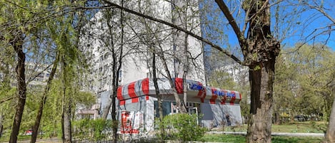 A building with a white exterior and red accents, surrounded by trees and greenery.