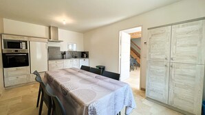 A compact kitchen with modern appliances, a dining area with a table and chairs, and a large wardrobe. - BIG HOUSE N°6 (Ferrières-la-Verrerie)