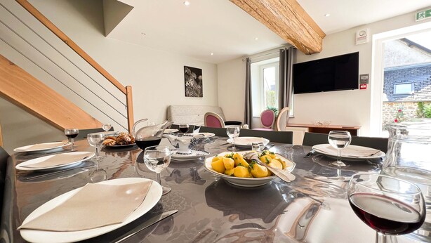 A dining area with a table set for four, including plates, glasses, and a bowl of fruit. - BIG HOUSE N°6 (Ferrières-la-Verrerie)
