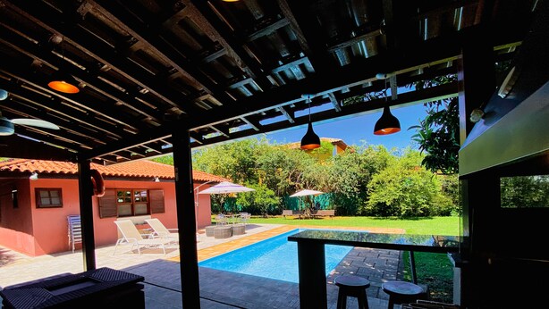 Ein Außenpoolbereich mit Liegestühlen und einer Bar.