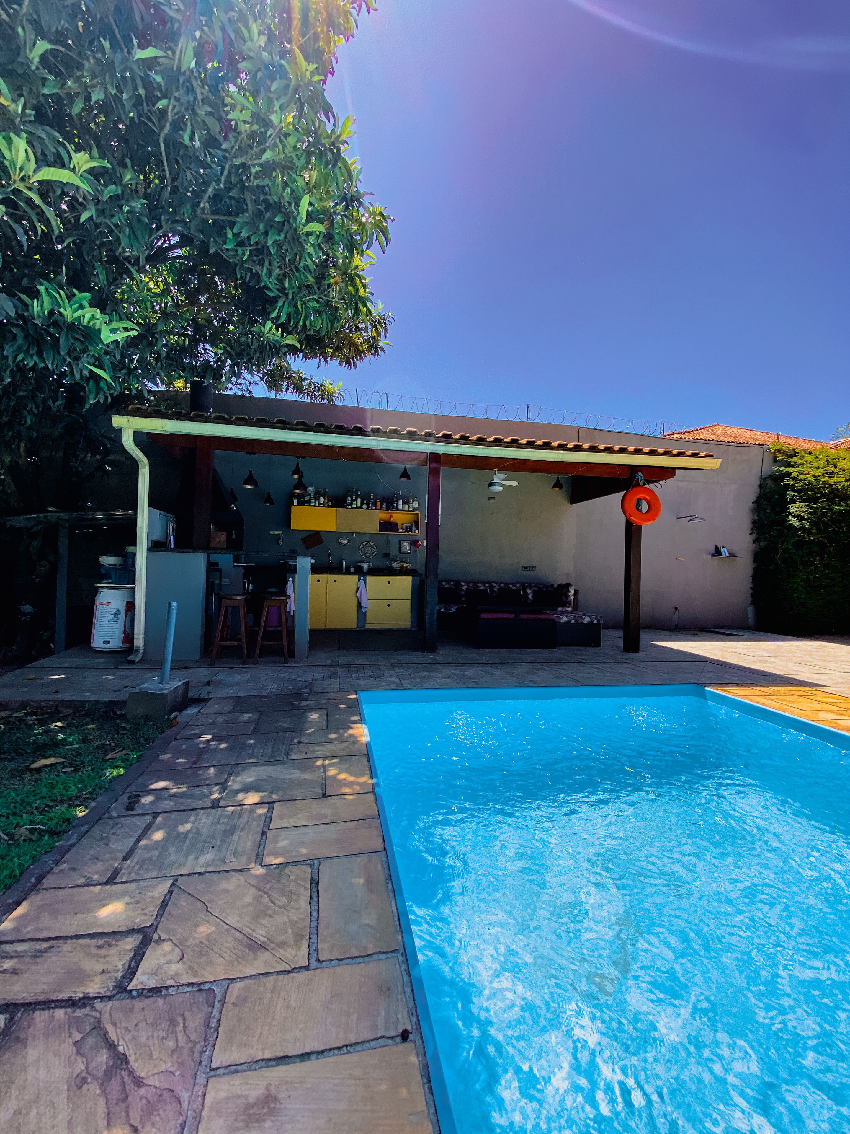 Un patio trasero con piscina, zona de barbacoa y un pequeño bar.