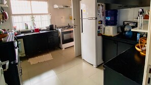 Eine moderne Küche mit Kühlschrank, Herd und Spüle. Ein Fenster sorgt für natürliches Licht und ein Wasserspender steht auf der Arbeitsfläche.