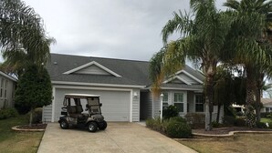 Ein Wohnhaus mit Garage, ein Golfwagen davor und Palmen.