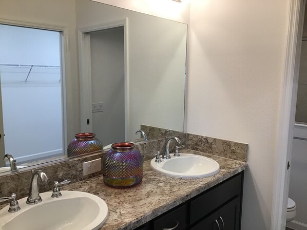 A bathroom with two sinks, a large mirror, and a door leading to another room. - 2173 Biller Cir (Wildwood)