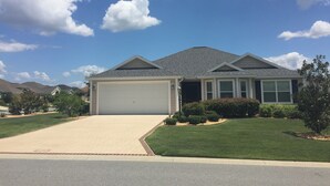 A single-story house with a garage, surrounded by well-maintained lawns and a clear sky. - 1416 Hillstream St (Wildwood)