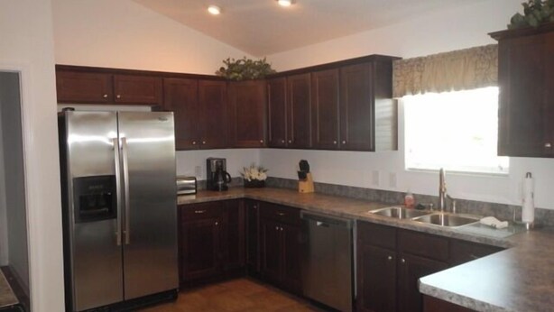 A modern kitchen with dark wooden cabinets, stainless steel appliances, and a granite countertop. - 1416 Hillstream St (Wildwood)