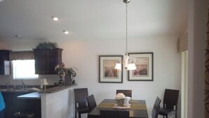 A modern kitchen with dark wooden cabinets, a central island, and pendant lighting. - 1416 Hillstream St (Wildwood)