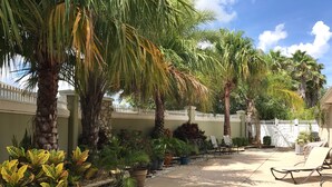 A courtyard with palm trees, potted plants, and outdoor seating. - 1023 Blue Heron Ave (The Villages)