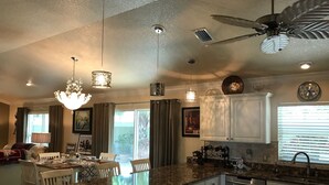 A spacious kitchen with white cabinets, a granite countertop, and a ceiling fan. - 1023 Blue Heron Ave (The Villages)