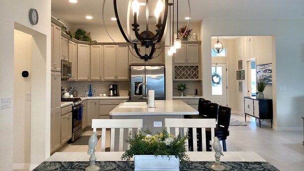 A modern kitchen with a central island, stainless steel appliances, and a decorative chandelier. - 2498 Lynette Avenue (Wildwood)