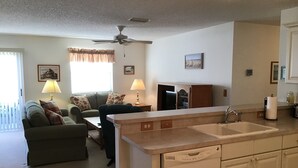 A compact living space with a kitchenette, a dining area, and a sofa with floral cushions. - 1614 Gibbes Way (The Villages)