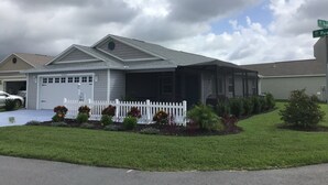 Une maison de plain-pied avec un garage, une véranda et une pelouse bien entretenue.
