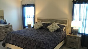 Une chambre à coucher comprenant un lit, deux tables de chevet, une commode, une lampe et une coiffeuse.