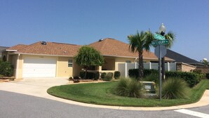 Una casa residencial con garaje, césped cuidado y una señal de calle que indica la intersección de Teasdale St y Waterbury Pl.